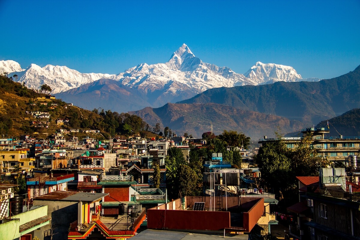 A breathtaking aerial view of the Annapurna range in Nepal, with a helicopter landing on a ridge.